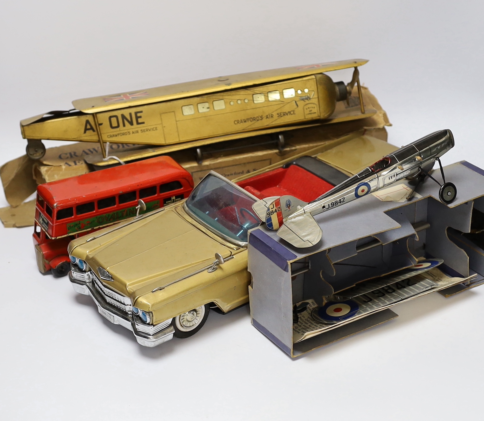 Four tinplate toys; a Frog Interceptor Fighter, a Bandai battery powered Cadillac Convertible (4025), a Crawford’s Biscuits Aeroplane and a clockwork Tri-ang Minic London Transport Double deck bus